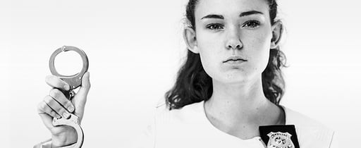Young woman wearing a badge and holding handcuffs