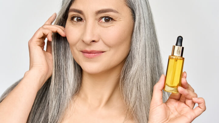 woman with grey hair holding perfume