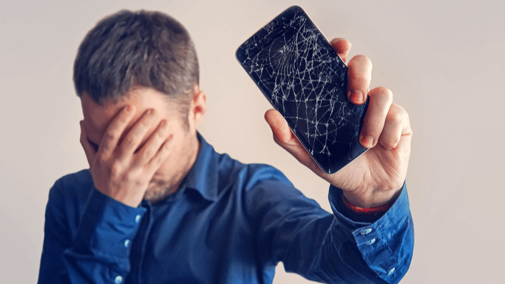 guy is holding a black smartphone with a broken display