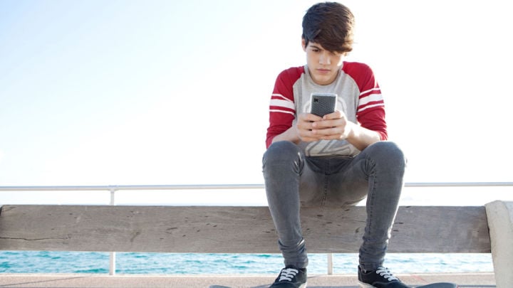 teenager on the beach using his phone