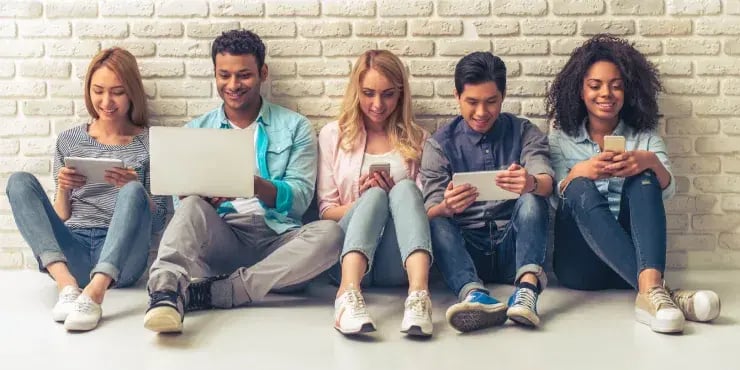 young people sitting on the floor all using mobile devices