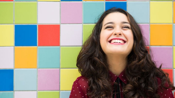 Happy girl laughing against a colorful tiles background