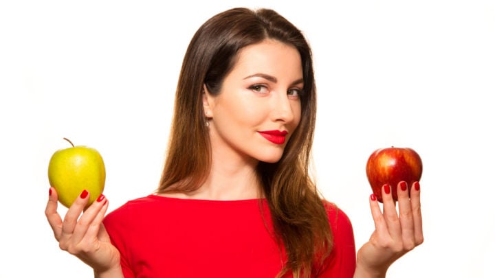 woman holding green and red apple