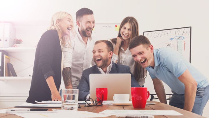 Happy business people laugh near laptop in the office