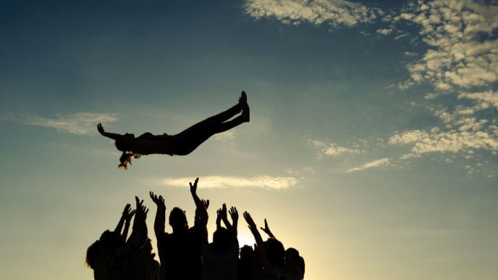 group of people throwing and catching a person in the air