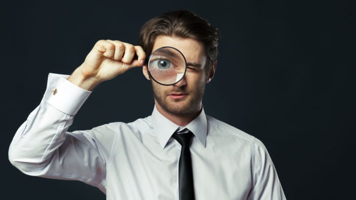 man looking in magnifying glass