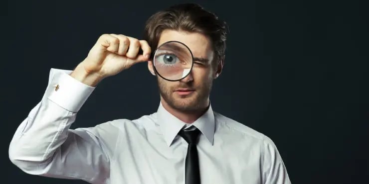 man looking in magnifying glass