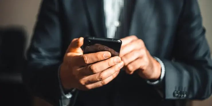 man in suit looking at his smartphone
