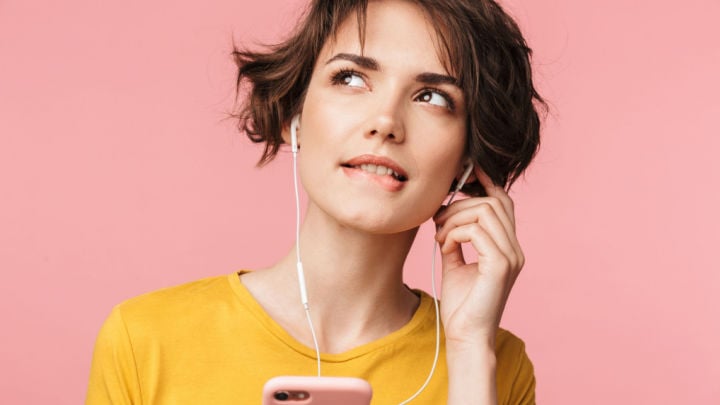 woman with phone fiddling with her headphones