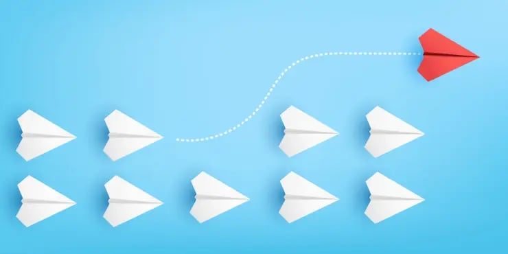 a red paper plane separates from a group of white planes