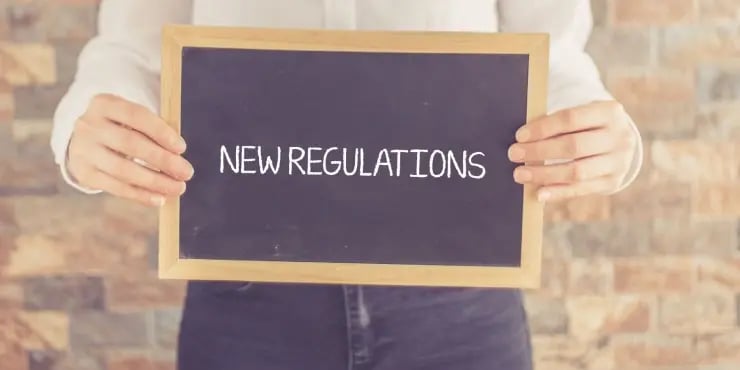 man holding sign that says New Regulations