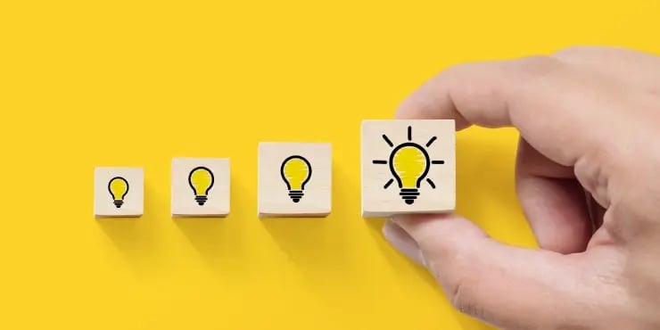 a hand placing blogs with lightbulbs on them in size order