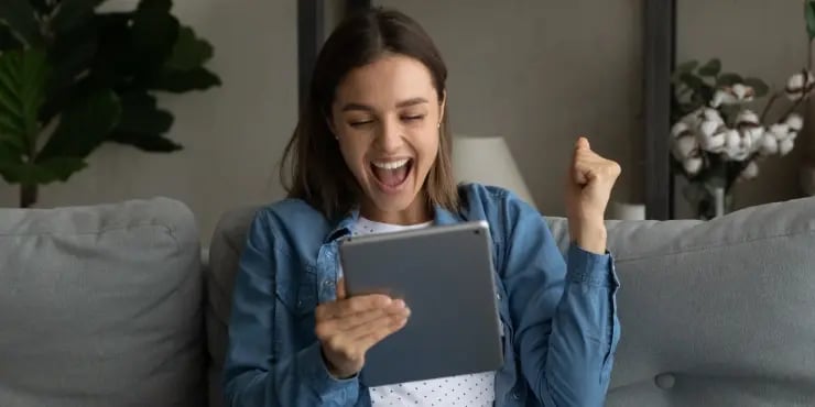 excited woman looking at her tablet