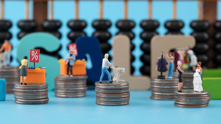 miniature figurines shopping on stacks of coins