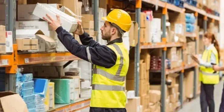 man pulling a box off a shelf in a warehouse