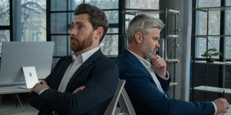 2 disgruntled businessmen looking away from each other