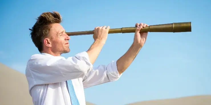 businessman looking through a telescope in the desert