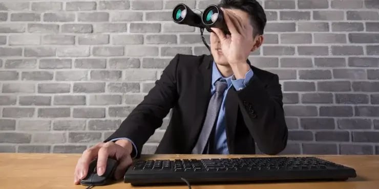 businessman at his desk using binoculars to look around