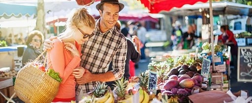 A couple checking out produce in a street marketplace